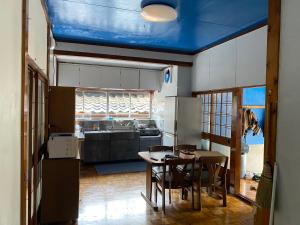 a kitchen with a blue ceiling with a table and chairs at 釣り宿yasakabase guesthouse in Sado