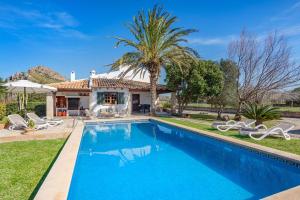 a swimming pool in front of a house with a palm tree at Villa Can Deyá in Port de Pollensa