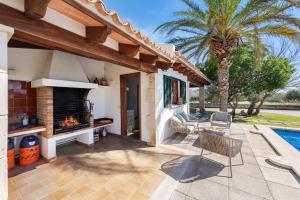 a patio with a fireplace next to a palm tree at Villa Can Deyá in Port de Pollensa