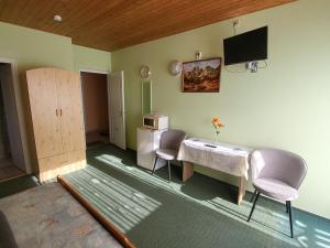 a room with two chairs and a table and a tv at Mimóza Vendégház - Csaba Vendégház in Balatonszemes