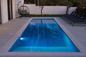 a swimming pool with blue water in a yard at Villa Sensei in Linardići