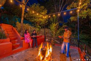 a group of people standing around a fire at night at Zostel Munnar in Devikolam
