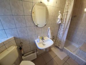 a bathroom with a sink and a toilet and a mirror at Mimóza Vendégház - Csaba Vendégház in Balatonszemes