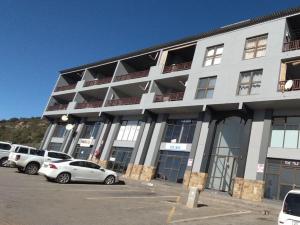 a white building with cars parked in a parking lot at Vene's Place in Mossel Bay