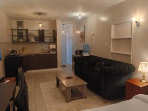 a living room with a black couch and a table at Legatus Cozy Studios B - Ongata Rongai Furnished Apartment with Swimming pool in Nairobi +6 photos