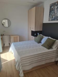 a bedroom with a large white bed with green pillows at Apartamentos EL FONTANAR in Almagro