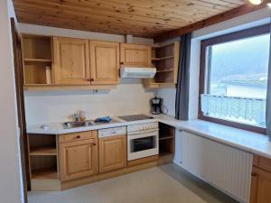 a small kitchen with wooden cabinets and a window at Ferienwohnung Sankt Josef 2 in Bodensdorf