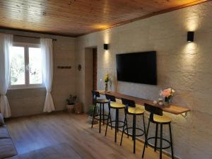 a living room with a bar with stools and a tv at Kefalonia Olive House private pool in Xi