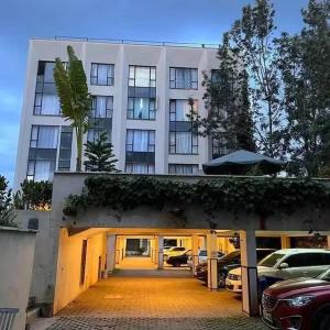 a large white building with cars parked in front of it at Legatus Cozy Studios B - Ongata Rongai Furnished Apartment with Swimming pool in Nairobi