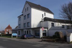 ein weißes Gebäude mit einem davor geparkt in der Unterkunft Hotel Meeresfriede in Cuxhaven