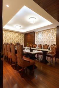 a dining room with tables and chairs and a wall at The Grand Ambassador in Phagwāra