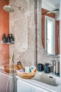 a bathroom sink with a mirror and baskets on it at Modern City Studio with Balcony Columbus Apartment in Chios