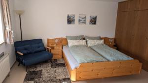 a bedroom with a wooden bed and a blue chair at FeWo im Grünen in Häusern