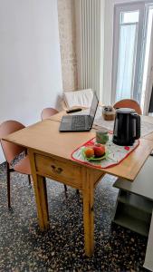 a wooden table with a laptop and fruit on it at Saliscendi in centro in Putignano