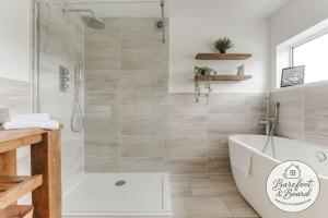 a bathroom with a bath tub and a shower at Luxury 2-Bed House in Stevenage Sleeps 6 Free Parking Barefoot & Board in Shephall +26 photos
