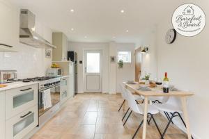 a kitchen with a table and chairs and a kitchen with white appliances at Luxury 2-Bed House in Stevenage Sleeps 6 Free Parking Barefoot & Board in Shephall