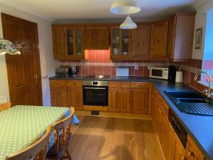 a kitchen with wooden cabinets and a table in it at Stony Thwaite in Reeth