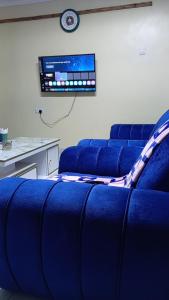 a room with blue couches and a tv on a wall at KiQao in Nakuru