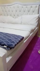 a white bed with a blue blanket on it at KiQao in Nakuru