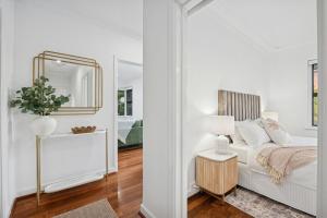 a white bedroom with a bed and a mirror at Beach House Family Friendly Enclosed Yard in Rockingham