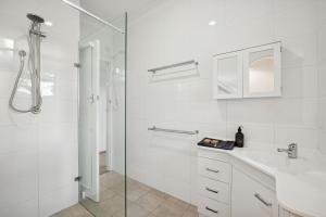 a white bathroom with a shower and a sink at Beach House Family Friendly Enclosed Yard in Rockingham +27 photos