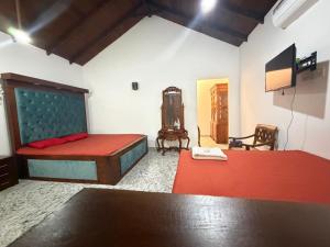 a bedroom with a bed and two chairs and a tv at Singha Holiday Bungalow in Ibbagomuwa