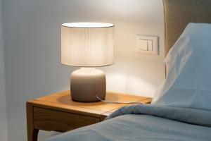 a lamp on a night stand next to a bed at Erbusco Charme Apartment in Erbusco