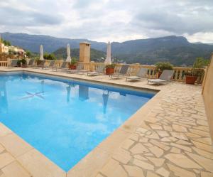 a large swimming pool with chairs and mountains in the background at Torre Picada Duplex in Port de Soller
