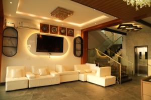a living room with white couches and a flat screen tv at Hotel Alak City in Vallakottai