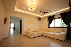 a living room with white couches and a ceiling fan at Hotel Alak City in Vallakottai