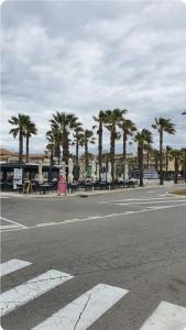 an empty street with palm trees and tables and chairs at Studio 2 pers à 50 m de la plage in Fleury