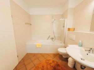 a bathroom with a sink and a toilet and a tub at Ferienwohnung Ammersee in Andechs +14 photos