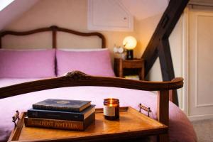 a bed with books and a candle on a table at The Corner House, Shipston-on-Stour in Shipston-on-Stour