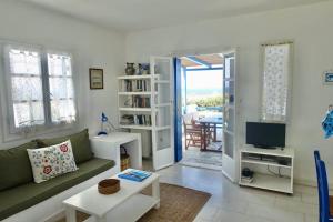 a living room with a couch and a tv at Villa G - Kamari Village in Kastraki