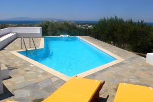a swimming pool with two yellow chairs on a patio at Villa G - Kamari Village in Kastraki