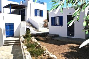 a white house with blue doors and stairs at Villa G - Kamari Village in Kastraki