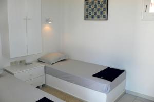 a small white bedroom with a bed and a cabinet at Villa G - Kamari Village in Kastraki +26 photos