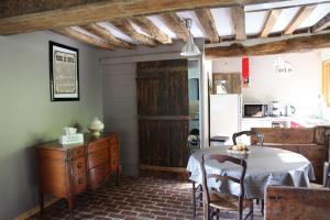 a dining room with a table and a kitchen at L'Etable d'Emile in Marais-Vernier