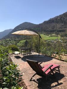 a patio with a table and a chair and an umbrella at Bergromantik Ferienwohnung Nesterl mit eigener Sauna und Bergblick in Marktschellenberg