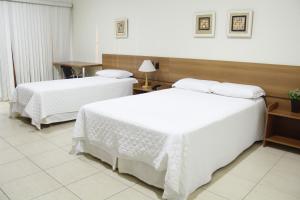 a hotel room with two beds with white sheets at Buriti Hotel in Jataí +36 photos
