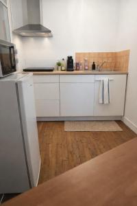 a kitchen with white cabinets and a wooden floor at Functional and convenient apartment avec wifi in La Machine