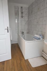 a white bath tub in a bathroom with a wooden floor at Functional and convenient apartment avec wifi in La Machine