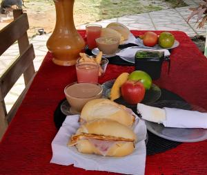 a table with a sandwich and apples and drinks at Pousada O Povorello - a 1 minuto a pé da Praia Grande da Baía do Sol in Mosqueiro