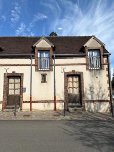 an old brick building with two windows on a street at Appartement Maisonnette pour 4 personnes in La Ferté-Vidame