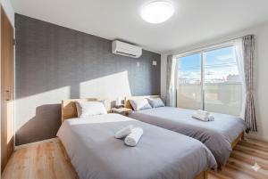 two beds in a room with a window at THE SUN in Sapporo