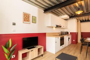 a living room with a tv and a red wall at Zest Vendome - Saxe Gambetta in Lyon