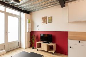 a living room with a tv and a red wall at Zest Vendome - Saxe Gambetta in Lyon