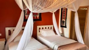 two beds in a room with white drapes at Volcano View in Ruhengeri