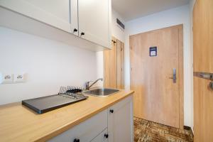 a kitchen with a sink and a wooden door at RentPlanet - Welle Resort in Grzybowo