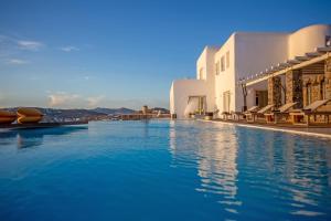 a swimming pool with blue water in front of buildings at Maison Haute Mykonos in Ornos